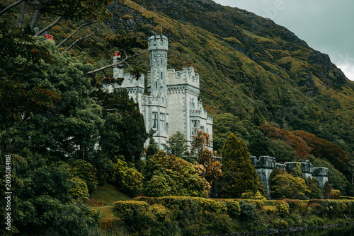 Foto Historic Kylemore Abbey castle and lake surrounded by green forest in Connemara,