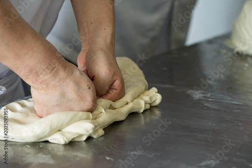 Foto Pastry chef kneading dough by hand on workbench