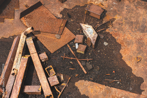 Close-up of rusted metal surfaces, including rusty nails and sheet metal in various tones of corrosion. Textured abstract industrial background with warm rusty colors.