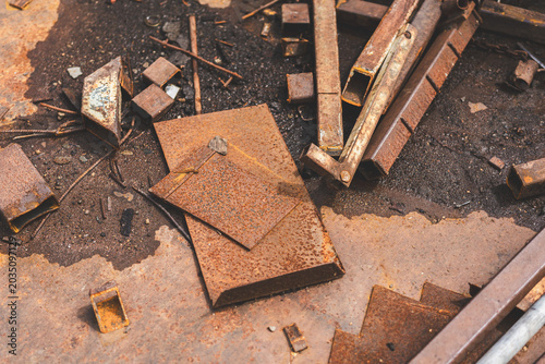 Close-up of rusted metal surfaces, including rusty nails and sheet metal in various tones of corrosion. Textured abstract industrial background with warm rusty colors.