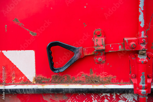 Obraz na plátně Red industrial door with weathered metal latch and peeling paint showing corrosi