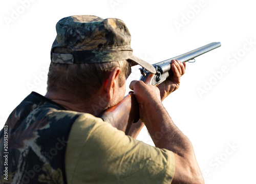 An adult hunter hunts in the autumn countryside. He fires a shotgun.