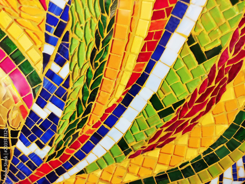 Close-up of a colorful artistic mosaic made of glass tiles in different shapes and sizes. Abstract pattern, vibrant colors, detailed texture, and handcrafted design.
