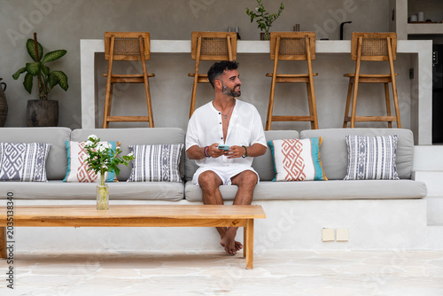 Man relaxing on a sofa holding a smartphone in a modern lounge area