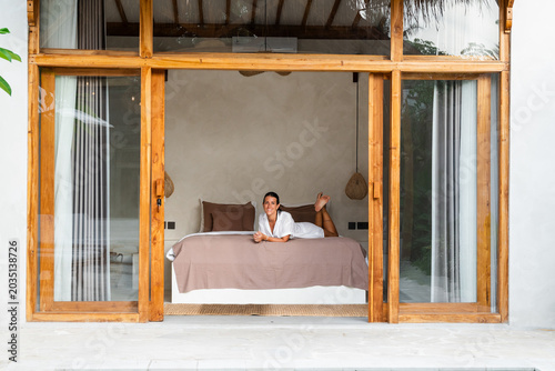 Woman resting on a bed inside a modern tropical villa bedroom
