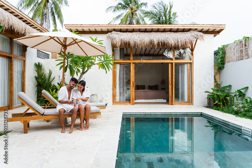 Young couple enjoying tropical vacation by swimming pool at modern resort villa