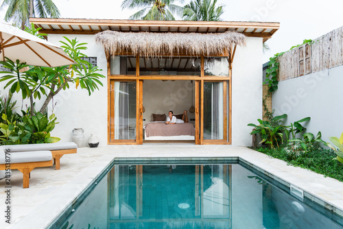 Woman enjoying a luxury holiday vacation from her private villa bedroom opening to a swimming pool