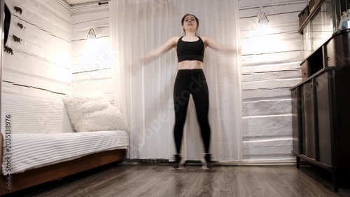 Caucasian woman doing an exercise Jumping Jacks on floor at home. Fast workout. Morning warmup. Person strengthening the muscles of legs, endurance and balance. Strong sporty body. HQ 4k footage.