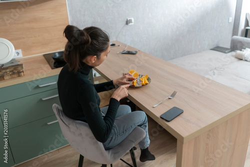 Woman enjoys breakfast at a kitchen table while seated on a chair