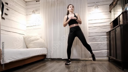 Caucasian woman doing exercise stepping from one leg to another on floor at home. Person workout. Strengthening the muscles of legs and balance. Strong body. Sporty lifestyle. High quality 4k footage.