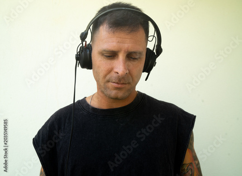 Electronic music DJ with headphones on. Person with tattoos and a modern look