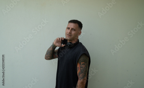 Electronic music DJ with headphones on. Person with tattoos and a modern look