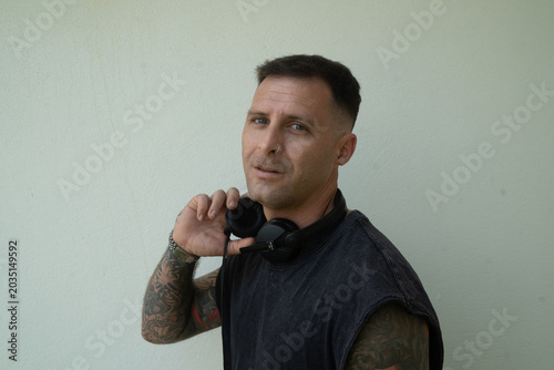 Electronic music DJ with headphones on. Person with tattoos and a modern look