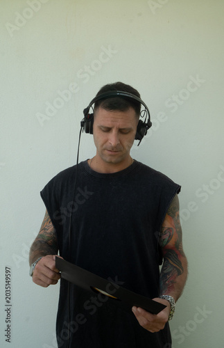 Electronic music DJ with headphones on. Person with tattoos and a modern look