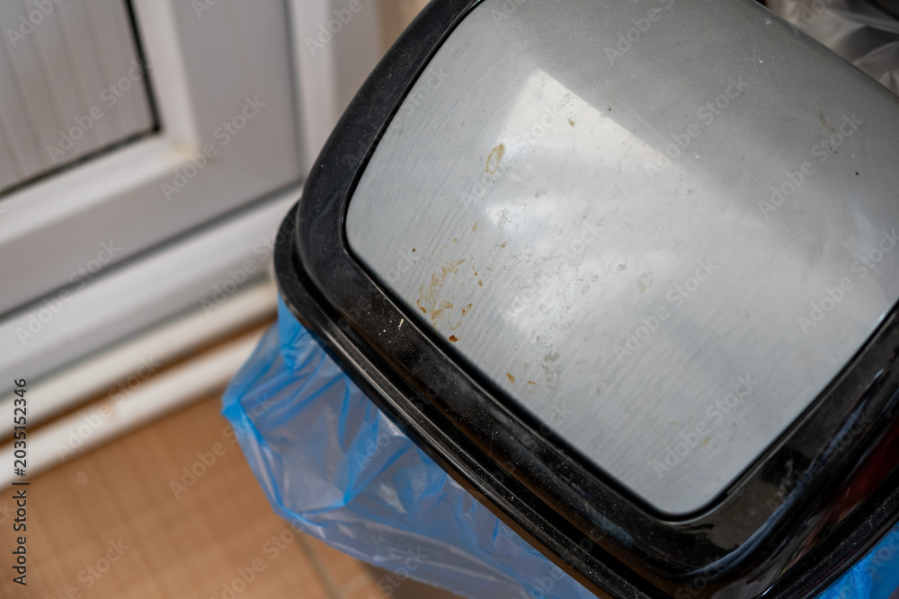 Obraz premium Stainless steel trash can lid with accumulated dirt and grime, showing need for cleaning and hygiene in a domestic kitchen