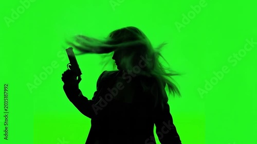 A woman is holding a gun against a green screen background with her hair moving for a crime, detective or mystery concept. Photo was animated with AI.