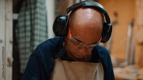 Photography Wood artisan concentrating on craft, wearing safety glasses and ear protection
