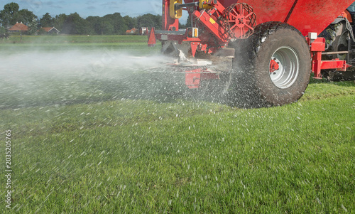Obraz na płótnie Spreading fertilizer with a tractor and spreader on a field of grass