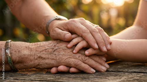 Three generations of hands intertwined, symbolizing love, care, and the enduring bond of family. A tender moment reflecting intergenerational support and connection, bathed in warm, natural light