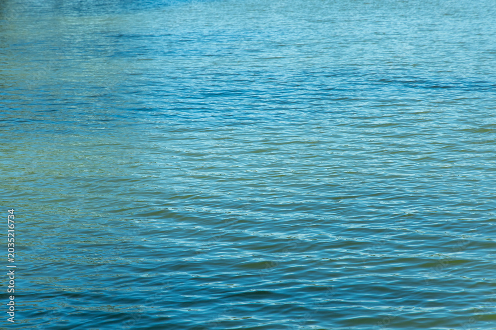 Obraz premium Clear water ripples in a lake under a sunny sky during mid afternoon in a natural setting