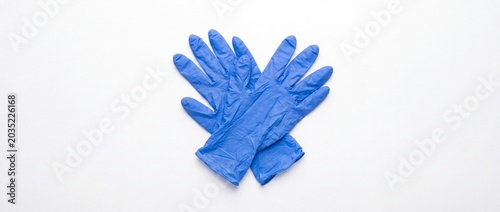 Pair of blue disposable nitrile medical gloves crossed on a white background. Protective rubber gloves for cleaning, healthcare, or surgery. Top view, flat lay
