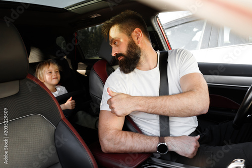 Obraz na plátně Father driver showing thumbs up sign to his little son in safety car seat