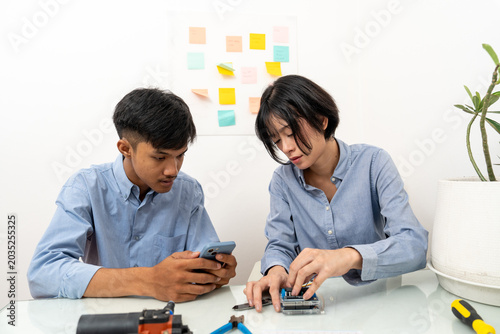 Young Asian woman and man connecting wires to the microcontroller.