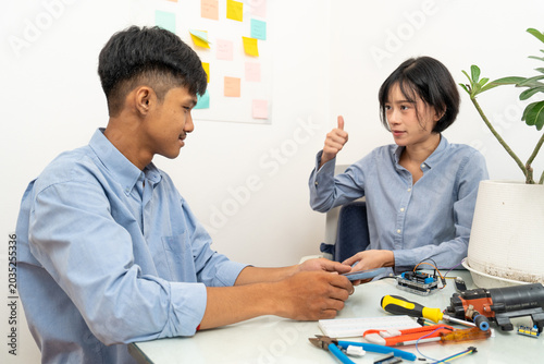 Young Asian woman and man connecting wires to the microcontroller.