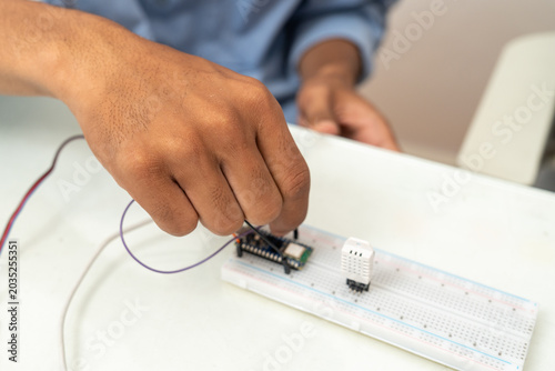 Close-up hand of man is connecting wires to the microcontroller.