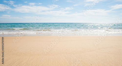 Minimal beach background with smooth sand, calm surf, pale turquoise water and wide open sky in a simple coastal composition