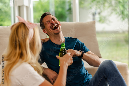 Friends Enjoy a Fun Time Laughing and Sharing Drinks Inside a Cozy Living Room During a Sunny Afternoon Gathering