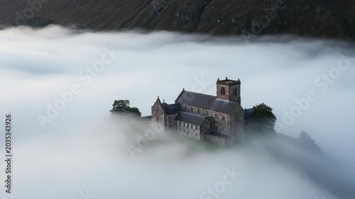 Historic church surrounded by misty fog on mountain landscape  