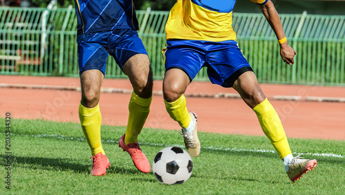 Fotografia Closeup of professional football players tackling for the ball on a sunny grass