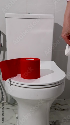 Hand placing toilet paper roll on toilet seat. Woman using bathroom supply for hygiene and health care. Concept of managing intestinal symptom and medical prevention with personal sanitation