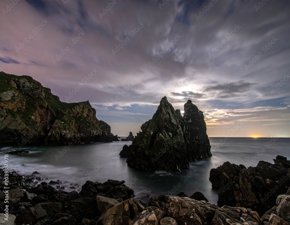 Naklejka premium Dramatic rocky coastline at sunset ocean.