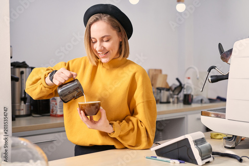 Barista pouring milk, making latte art, working at coffee shop