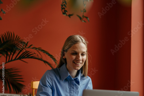 Fotografie Smiling woman using laptop for casual home office work