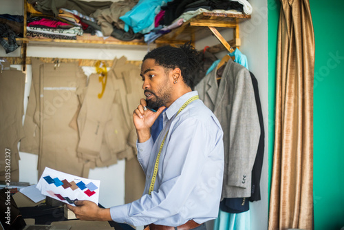 Photography Photo showing african american tailor discussing fabric swatches on phone -stock