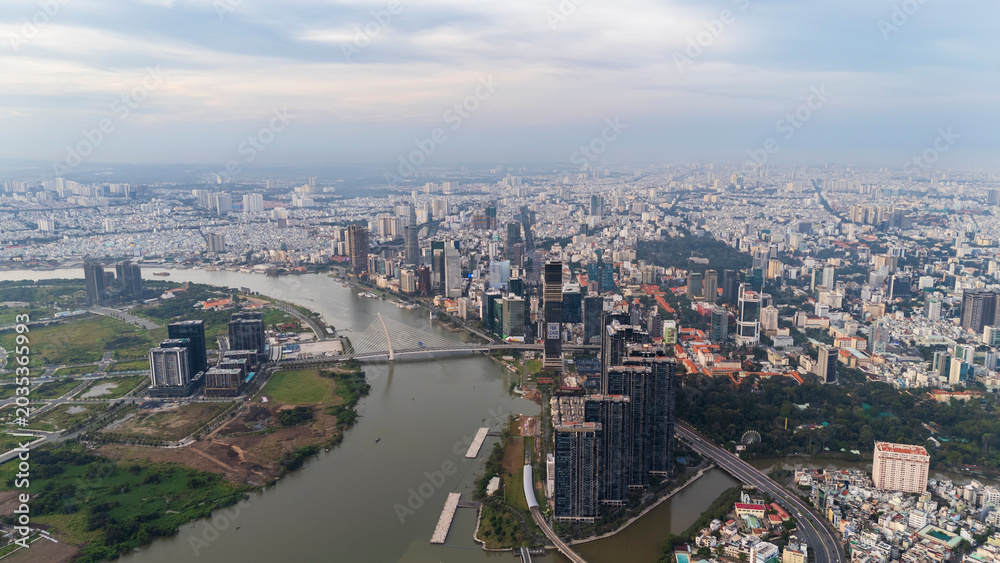 Fototapeta premium Drone aerial panoramic view of the Saigon River, Ba Son Bridge, and the modern city skyline of District 1 in Ho Chi Minh City, Vietnam.