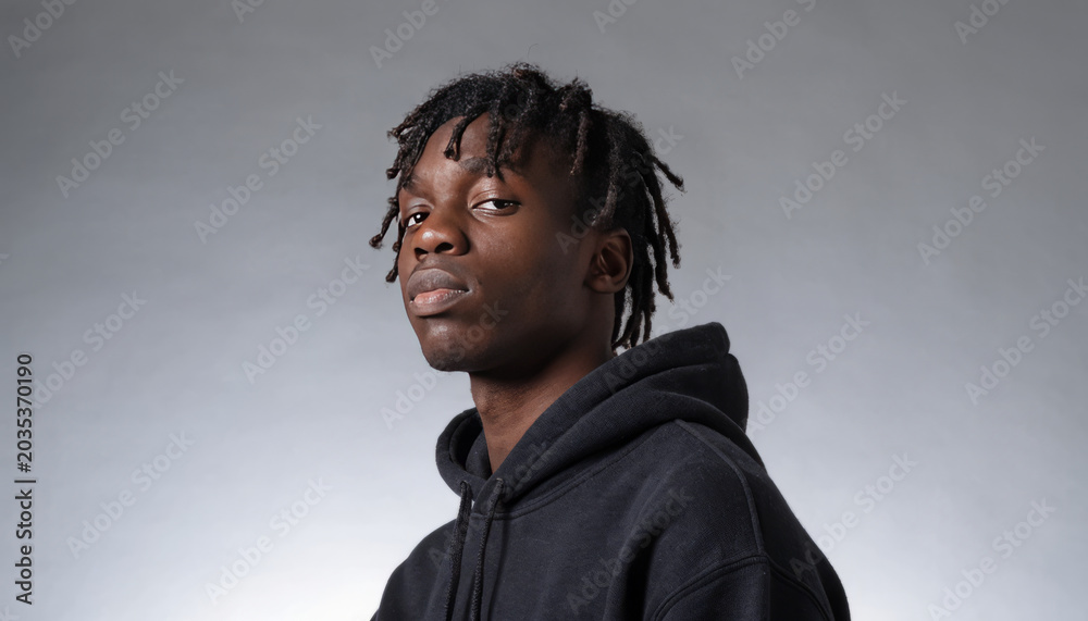 Fototapeta premium Young man portrait black hoodie studio lighting grey background moody expression casual style confident gaze modern hairstyle
