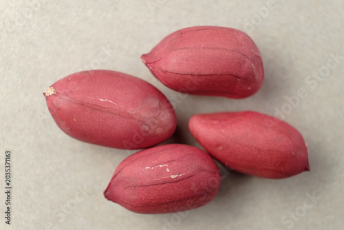 Bright red peanuts resting on a smooth grey surface under soft morning light
