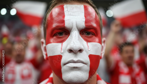 Danish football fan with painted flag face and tear showing sadness after national team defeat