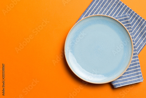 Cuadro en lienzo Top view on colored background empty round blue plate on tablecloth for food
