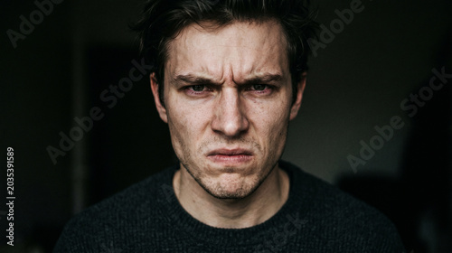 Intense portrait of a young man with a deeply furrowed brow and serious expression