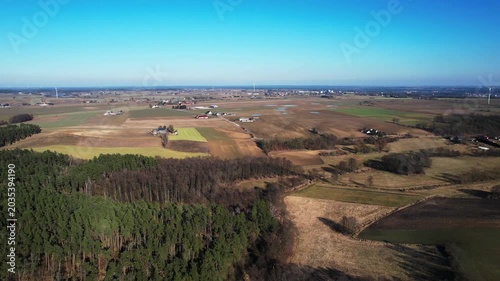 Backward drone flight above rural fields and forest landscape