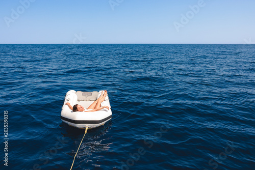 Quadro su tela Woman relaxing alone floating in dinghy on ocean