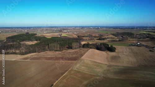 Backward drone flight over patchwork farmland and woodland groves