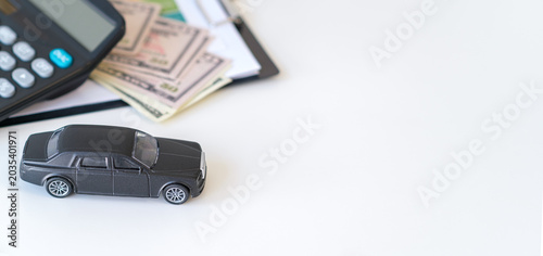 Фотография Black car model sits beside calculator and cash