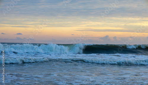 Powerful ocean waves rolling under a soft pastel sunset sky, creating a peaceful coastal scene ideal for travel blogs, tourism ads, relaxation themes, wallpapers, and nature-inspired designs.