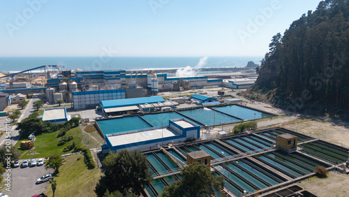 Aerial drone panning shot revealing water treatment pools and Arauco pulp mill in Constitucion, Chile.